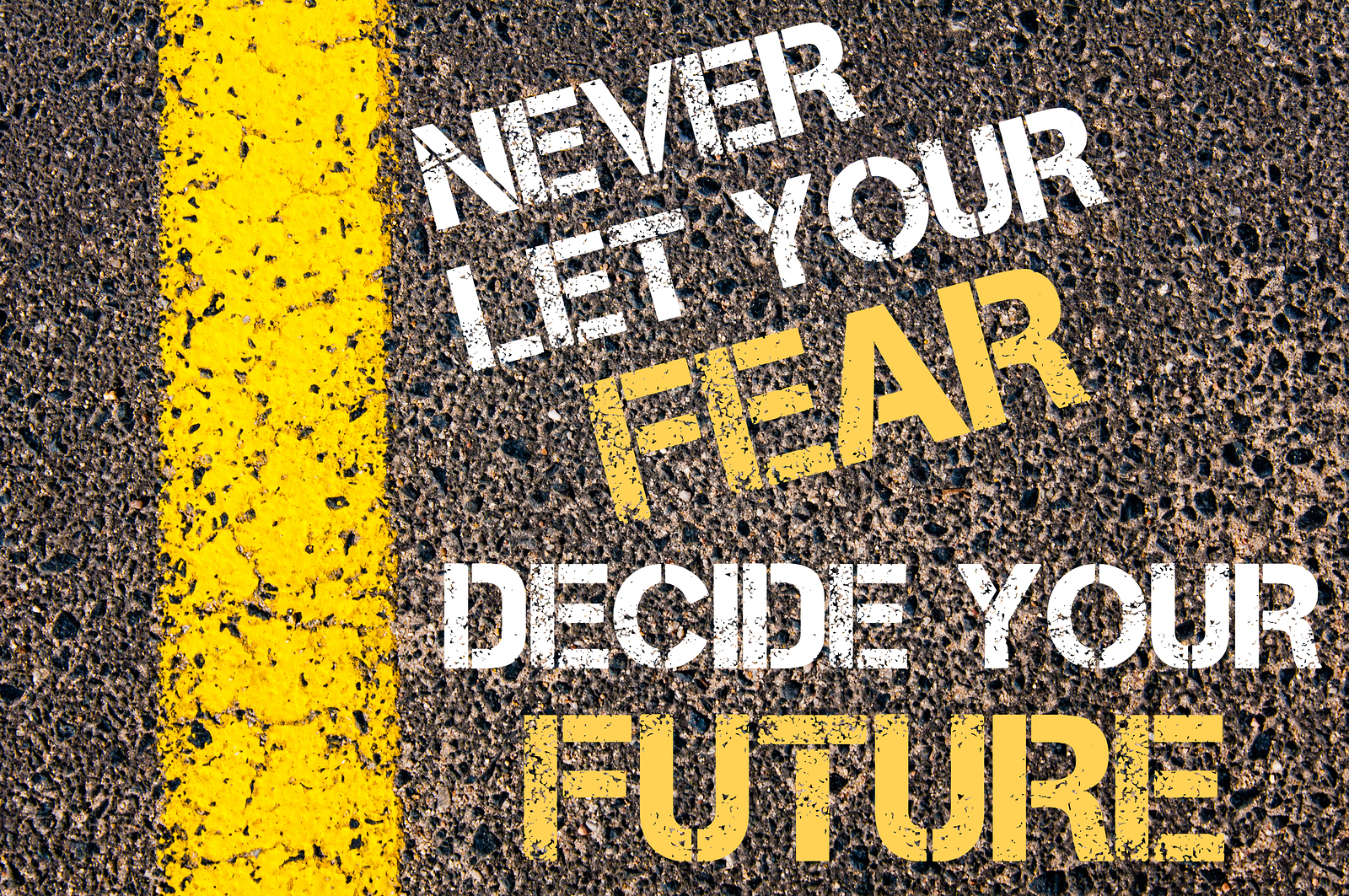 NEVER LET YOUR FEAR DECIDE YOUR FUTURE motivational quote. Yellow paint line on the road against asphalt background. Concept image